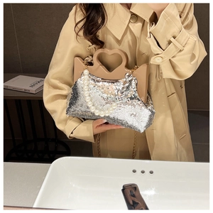 Detail of silver sequin tote bag featuring heart handle, pearls, and metal chain