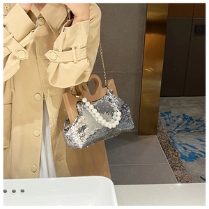 Close-up of silver sequin cloud bag featuring pearl handle and gold chain strap