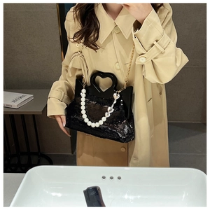 Detail of sequined tote bag featuring a rigid heart-shaped handle and pearl chain strap