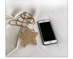 Detailed size comparison of the gold star-shaped hollow woven bag next to a smartphone