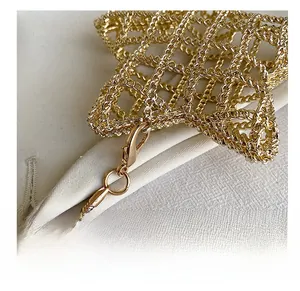 Detail of gold woven star bag with metallic hook and thin snake bone chain accessory