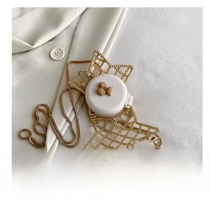 Macro detail of star-shaped metal cage bag with teddy bear accessory and gold chain