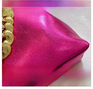 Macro shot of metallic fuchsia faux leather bag detail with thick gold chain link