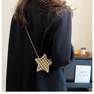 Detail view of a hollow star-shaped gold metal crossbody bag with fine chain strap