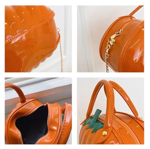 Detail of glossy orange pumpkin bag with gold metal zipper and green leaf handle