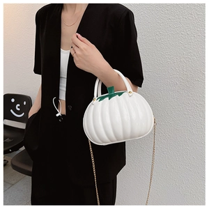 Chic white pumpkin-shaped handbag with green leaf detail and gold chain strap on model