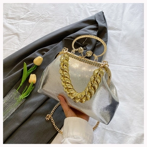 Detail of silver metallic handbag with chunky gold chain and retro clasp handle