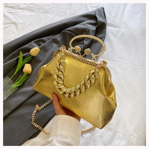 Detail of golden metallic evening clutch with pearl clasp and chunky chain strap