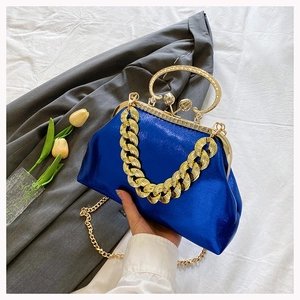 Close-up of royal blue evening bag with gold chain and circular handle details