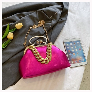 Macro shot of rose pink satin evening bag featuring gold chunky chain and crystal clasp