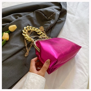 Detail of metallic pink kiss-lock bag with chunky gold chain and diamond clasp