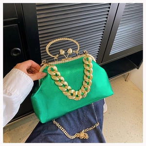 Close-up of vibrant green satin evening bag with chunky gold chain and rhinestone clasp