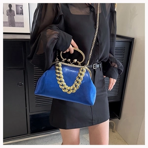 Detail of royal blue glitter handbag with chunky gold chain strap and metal clasp