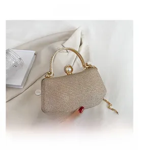 Close-up of champagne gold glitter evening bag with pearl clasp and metal handle