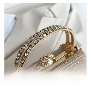Detail of rhinestone-encrusted handle and pearl clasp on champagne evening bag