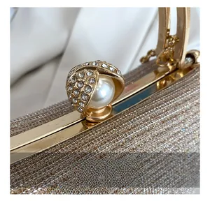 Detail of gold evening bag featuring sparkling fabric, rhinestone buckle, and pearl accent