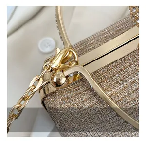 Close-up of golden evening bag showing glitter fabric, metal chain and lobster clasp detail