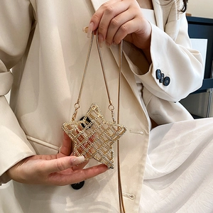 Star-shaped gold hollow out mini shoulder bag with fine metal chain strap on model