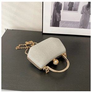 Close-up of evening clutch bag featuring rhinestone handle and large pearl clasp detail