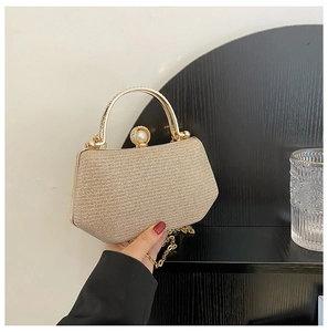 Close-up of golden glitter evening bag with pearl clasp and chain shoulder strap