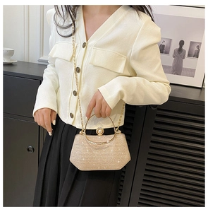Detail of gold glitter evening bag featuring metallic top handle and pearl clasp detail