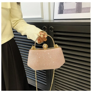 Detail of pink glitter evening clutch bag featuring a pearl clasp and gold metal handle