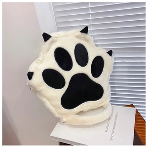 Close-up of plush cat paw backpack made of fluffy beige faux rabbit fur on book