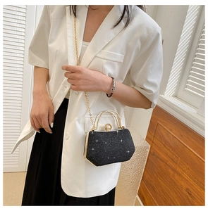 Detail of black sequin evening bag with gold handle and pearl clasp on a model