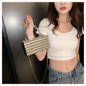 Bolso de mano dorado metalizado con textura plisada y cadena mostrado en modelo