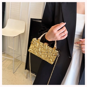 Detalle de bolso de noche dorado con textura de lava y correa de cadena metálica