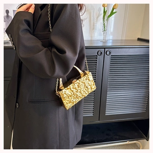 Detalle de bolso de fiesta dorado con textura de grietas y cadena desmontable