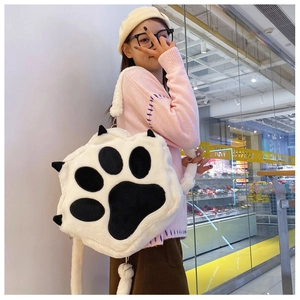Detailed side view of a fluffy cat paw plush backpack worn by a model in a casual setting