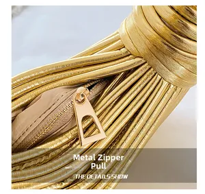 Detail of high-polish gold metal zipper on minimalist woven leather handbag texture