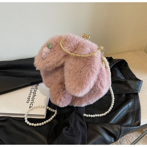 Detail of pink plush bag featuring purple carrot patch and elegant pearl strap accessory