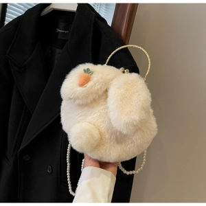 Detailed shot of plush rabbit bag featuring carrot embroidery and pearl chain strap