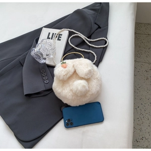 White plush bunny bag showing inner capacity next to a phone with pearl strap detail