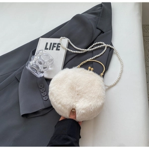 Detail of white faux fur round bag with gold metal handle and long pearl strap