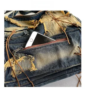 Detail of vintage denim tote bag showing metal zipper pocket and yellow fringe texture