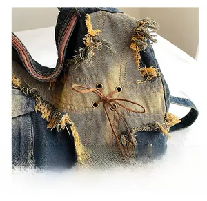 Detail of frayed edges and metal eyelets with brown lacing on denim tote bag