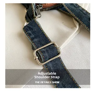 Detail of adjustable blue denim shoulder strap with silver buckle and yellow stitching