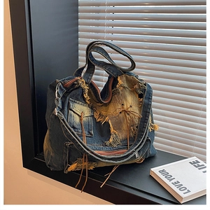 Detail of vintage patchwork denim bucket bag with distressed edges and side zipper pocket