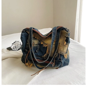Detail of vintage denim tote bag with frayed edges and multi-pocket metal zippers