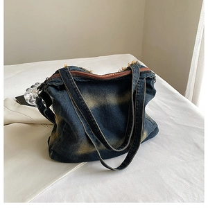 Detail of vintage washed denim tote bag featuring dual straps and brown zipper closure