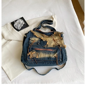 Detail of vintage denim crossbody bag featuring distressed fabric and multiple zipper pockets