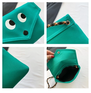 Vue détaillée du sac en toile verte montrant les coutures, l'imprimé yeux et la sangle
