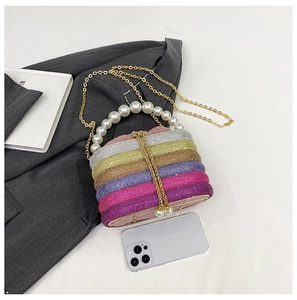 Detail der bunten Strass-Abendtasche mit Perlengriff und Goldquaste auf grauem Stoff