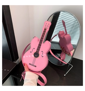 Detailansicht einer rosafarbenen Umhängetasche in Violinenform in einem Wandspiegel