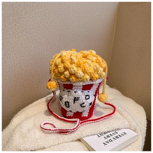 Detailed close-up of a handmade popcorn-shaped knitted crossbody bag with red stripes