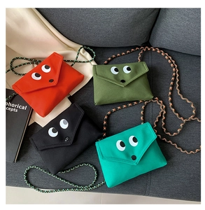 Détail de sacs bandoulière en toile colorée avec yeux de dessin animé et bandoulières