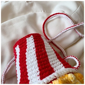 Detail showing red and white striped crochet popcorn bag with yellow fries design